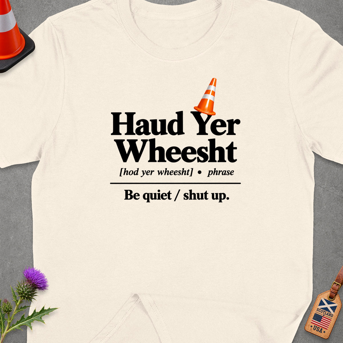 Cream t-shirt with "Haud Yer Wheesht" and its translation.