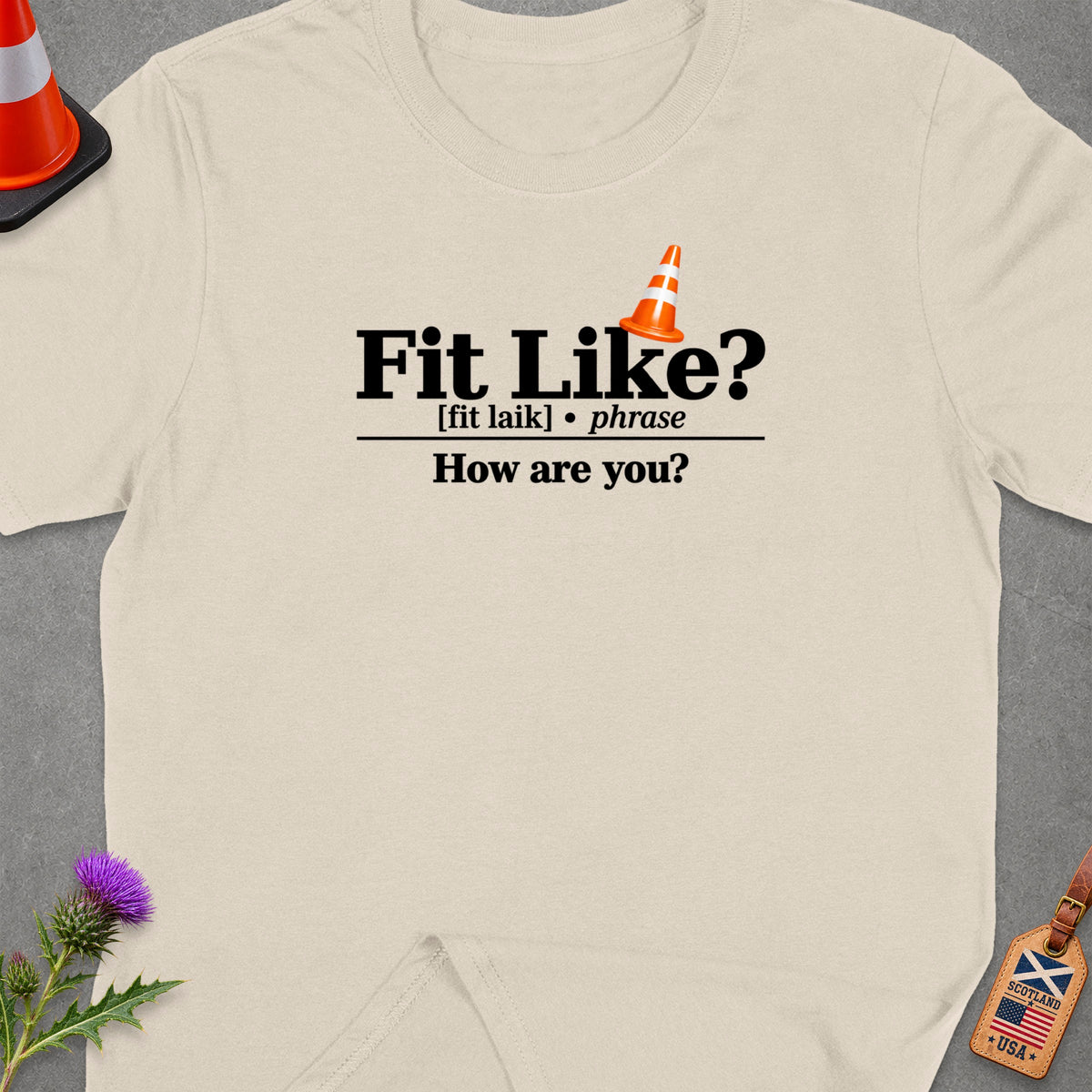 Cream t-shirt with "Fit Like? How are you?" text and traffic cone graphic.