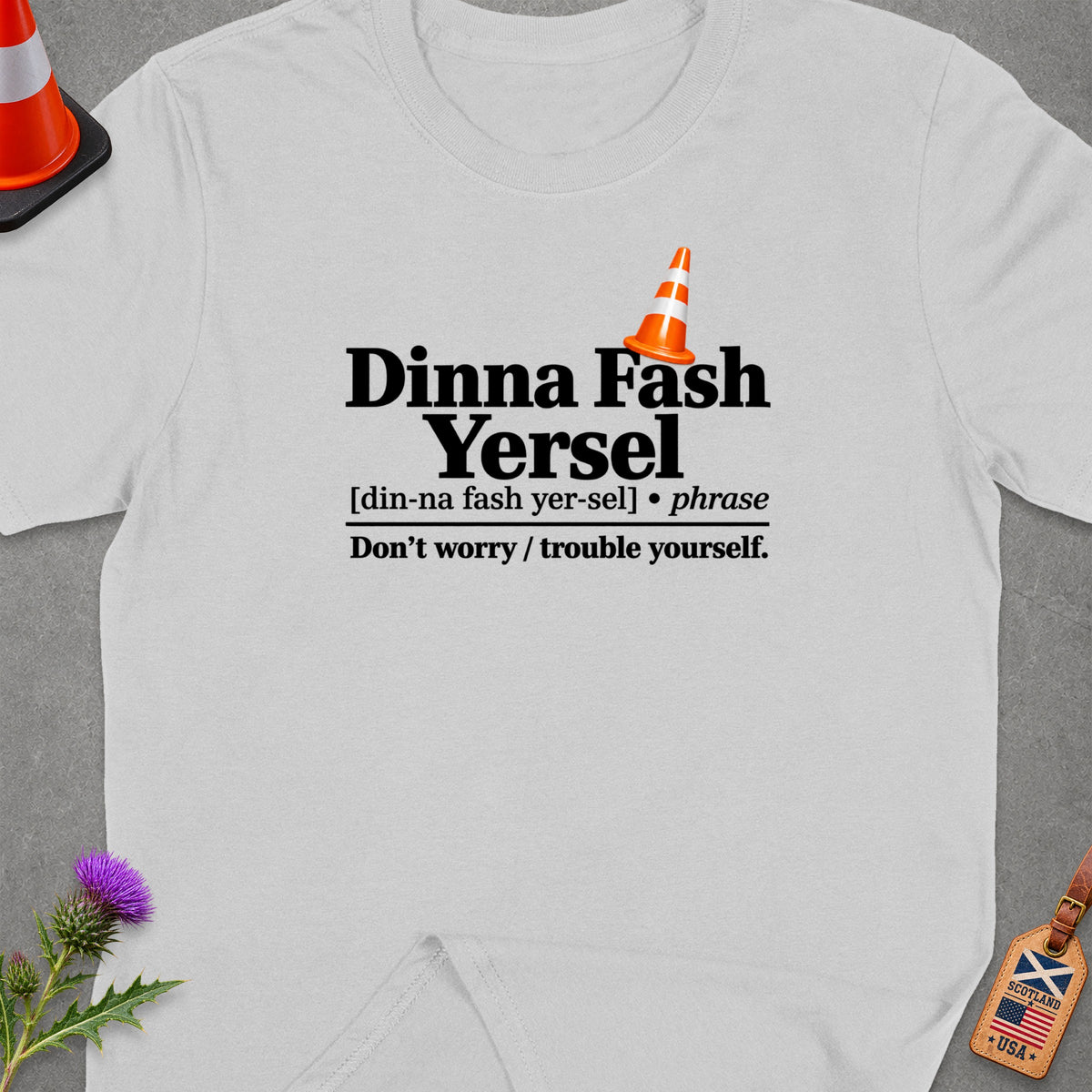 White t-shirt with "Dinna Fash Yersel" text and traffic cone graphic.