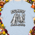 T-shirt with "Egg Heist" and two bunnies carrying a traffic cone and decorated egg.