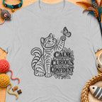 Striped cat reaches for butterfly next to text "Calm Curious Confident".
