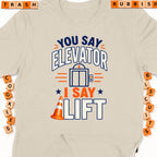 Cream t-shirt with graphic: "You say Elevator, I say Lift" and an elevator icon.
