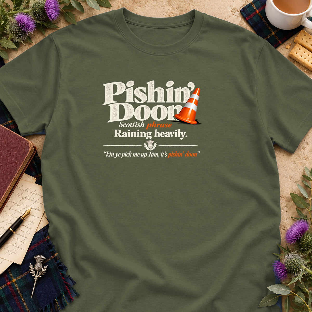 An army green t-shirt features white and orange text that reads "Pishin' Doon" alongside a traffic cone graphic.