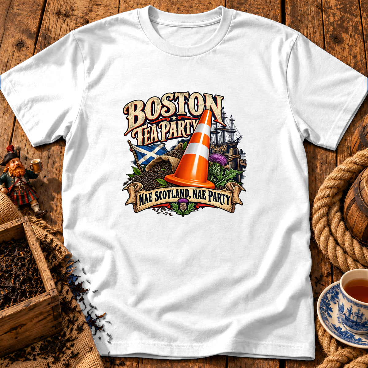 A white t-shirt featuring a colorful graphic with text reading Boston Tea Party and Nae Scotland, Nae Party.