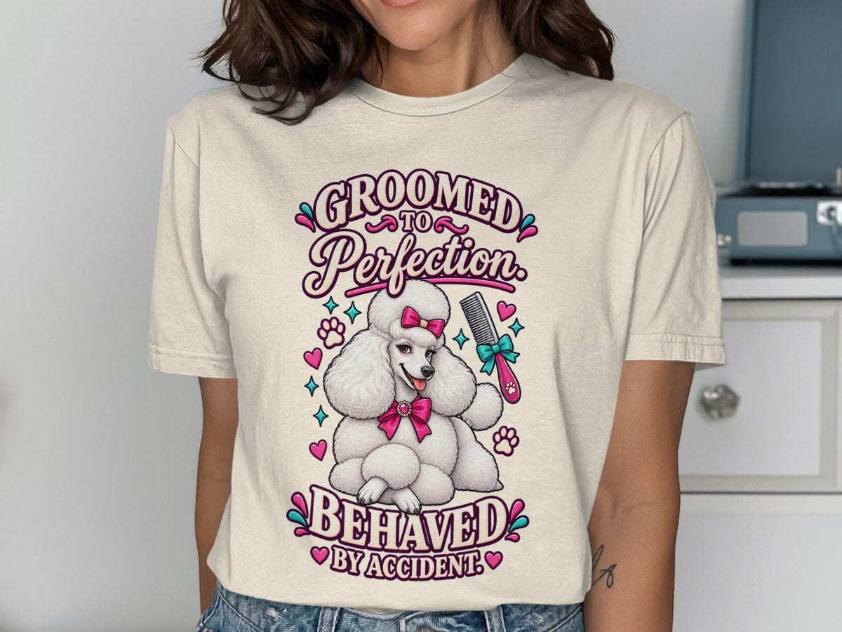 T-shirt graphic of a white poodle with pink bow and "Groomed to Perfection Behaved by Accident" text.
