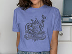 Maine Coon cat playing with butterfly graphic on a purple t-shirt.