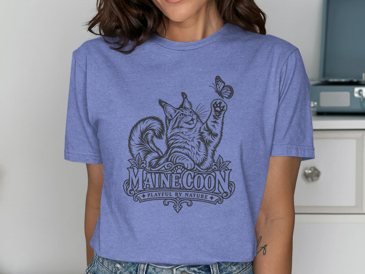 Maine Coon cat playing with butterfly graphic on a purple t-shirt.