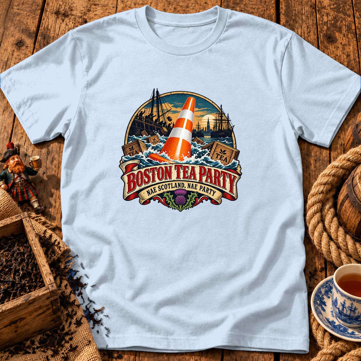 Light blue crewneck t-shirt featuring a graphic print of a traffic cone in turbulent ocean water, alongside ships, crates, and the text "Boston Tea Party / Nae Scotland, Nae Party".