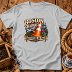 Light gray t-shirt with a Boston Tea Party graphic, Scottish flag, and traffic cone on a wooden table.