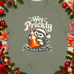 Hedgehog wearing Santa hat holding traffic cone with text "Wee Prickly" and "Nae Scotland, Nae Party".