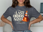 Dark gray t-shirt with "LAST ORDERS, SANTA." and a traffic cone in a tartan scarf.