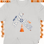 Grey t-shirt with "You say soccer, I say football" and a soccer ball.