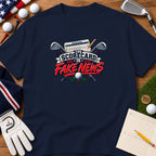 A navy blue t-shirt with a golf graphic featuring crossed clubs, a scorecard, and the text "The Scorecard is Fake News."