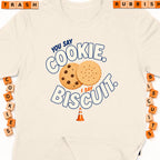 Cream t-shirt with graphic "You say cookie, I say biscuit" and cookies.