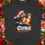 Santa cat wearing a Santa hat with a bow tie, touching an orange traffic cone. Text reads "Santa Claws Nae Scotland, Nae Party."
