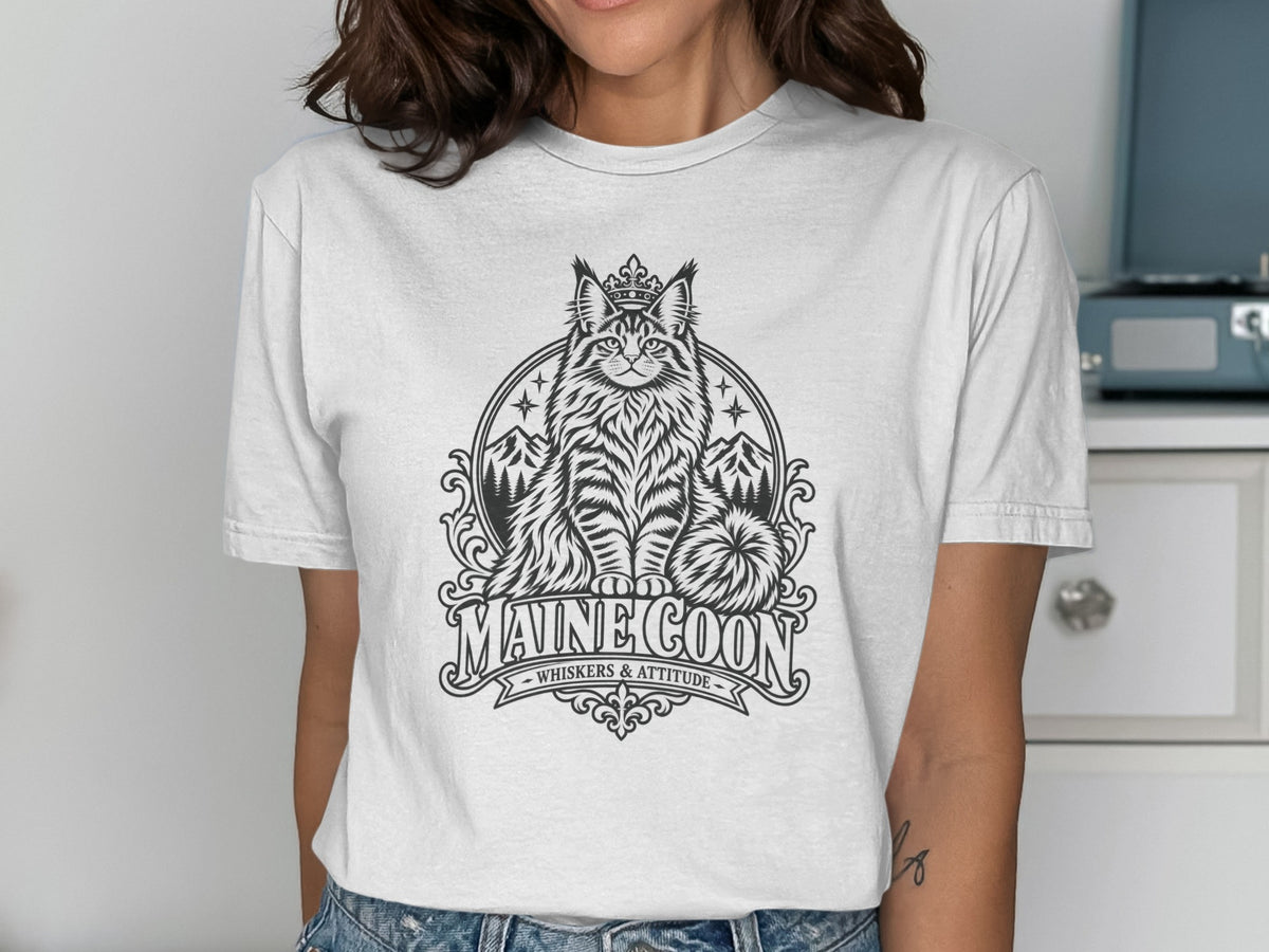 White t-shirt with black graphic of a crowned Maine Coon cat and text "MAINE COON WHISKERS & ATTITUDE".