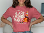 Red t-shirt with "LAST ORDERS, SANTA." text, orange cone with scarf, and holly.
