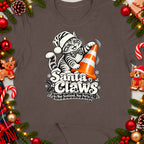T-shirt with a cartoon cat wearing a Santa hat, playing with a traffic cone, and the text "Santa Claws".