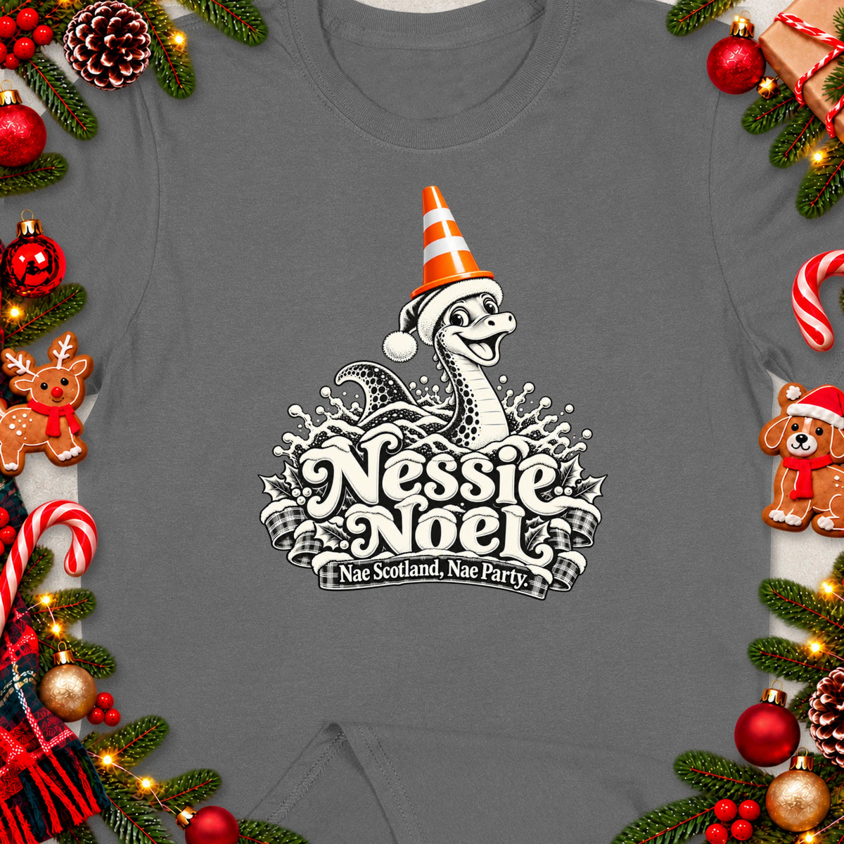 Grey t-shirt with Nessie Noel design featuring a Loch Ness Monster in festive attire and text.