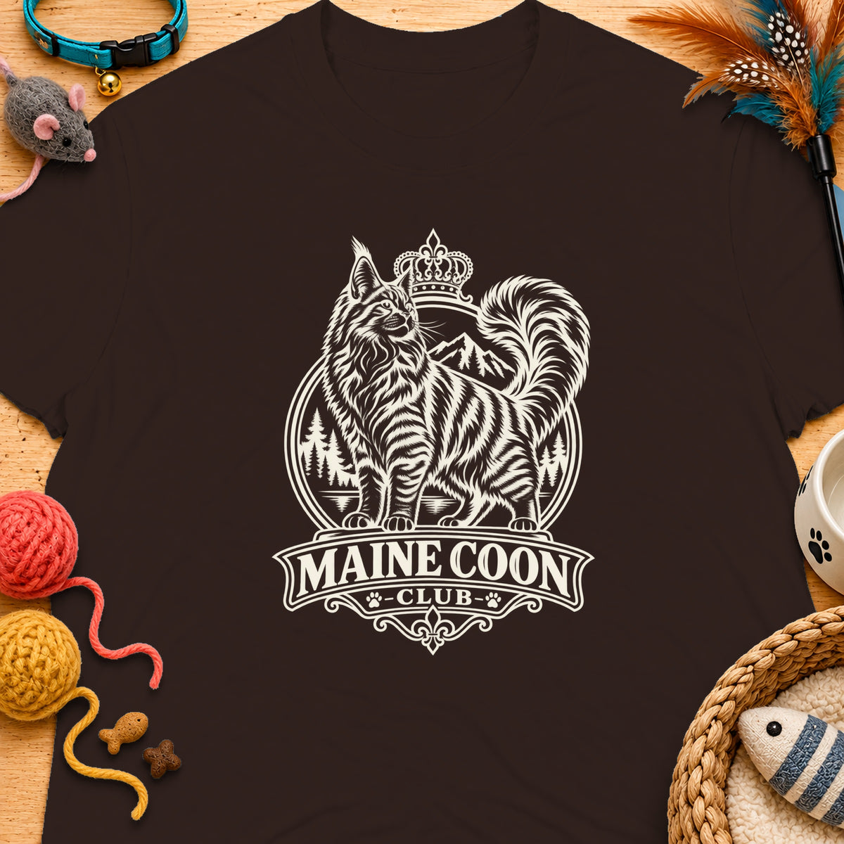 Brown t-shirt with a circular Maine Coon Club logo featuring a crowned cat and mountains.