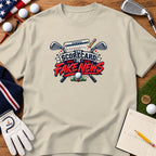 Beige t-shirt featuring a golf graphic with crossed clubs, a scorecard, and the text "The Scorecard is Fake News."