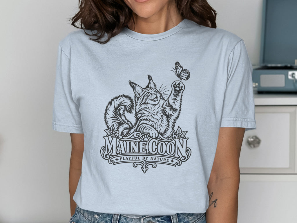 Light blue t-shirt with a black line drawing of a Maine Coon cat reaching for a butterfly.