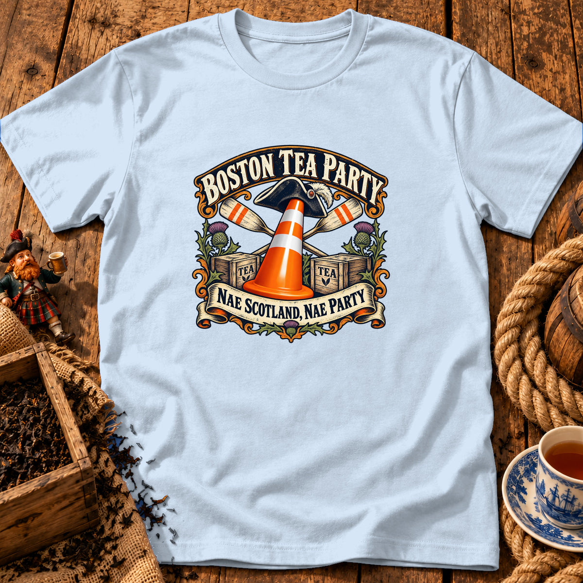 Light blue t-shirt displaying a vintage graphic with a traffic cone, oars, tea crates, and text.