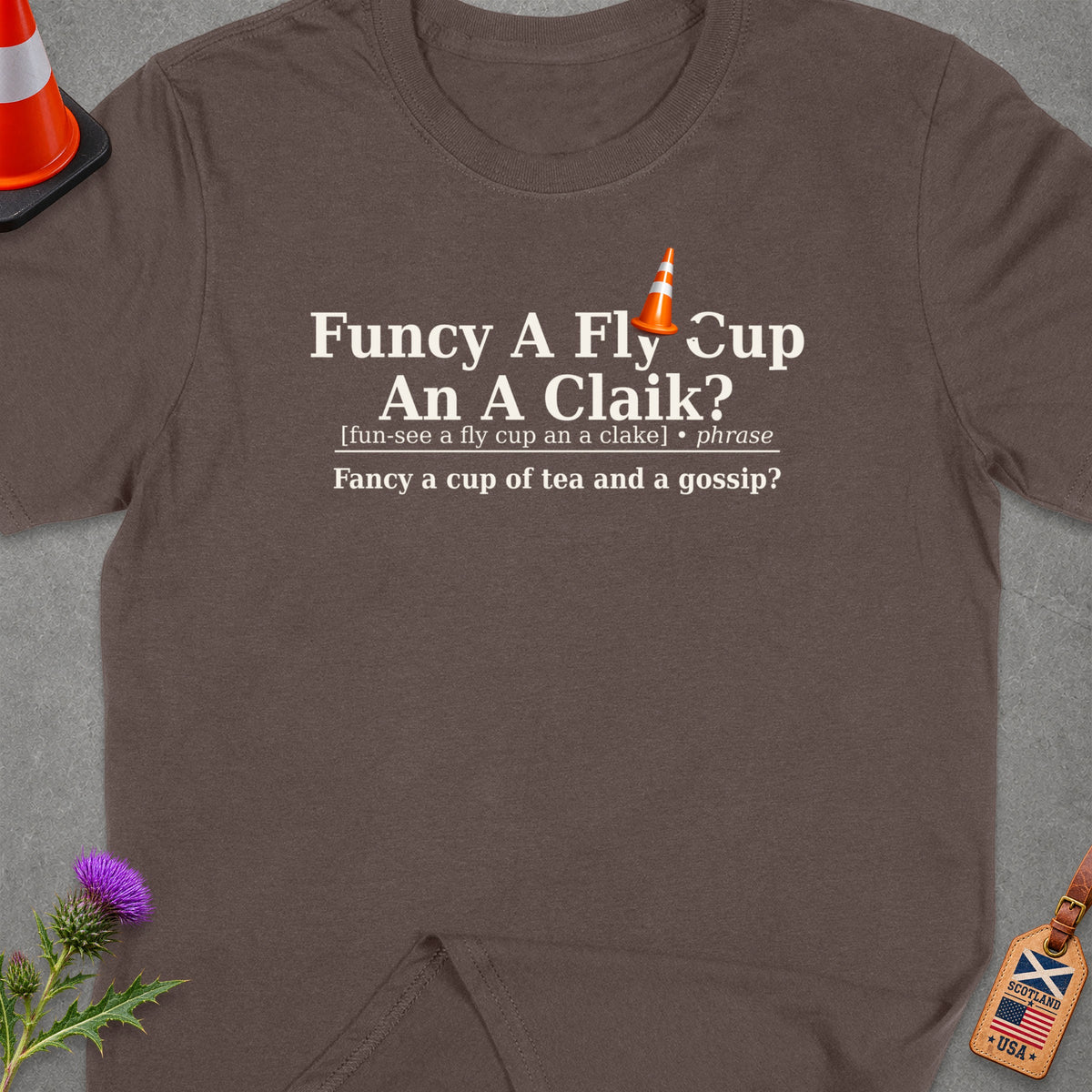 Brown t-shirt with "Funcy A Fly Cup An A Claik?" and definition.
