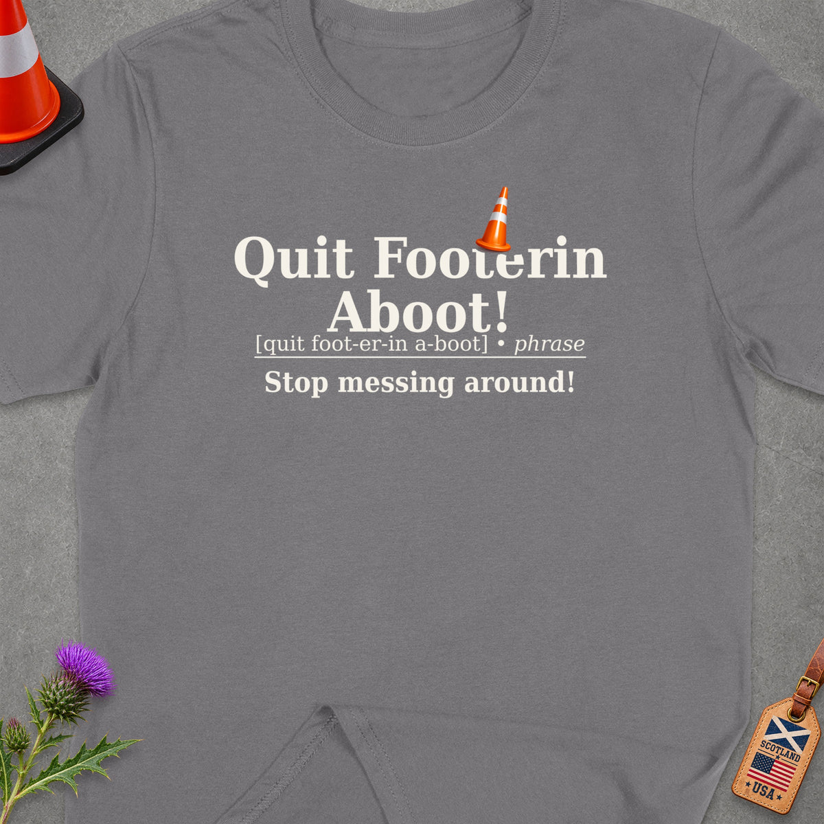 Grey t-shirt with text "Quit Footerin Aboot!" and traffic cone icon.