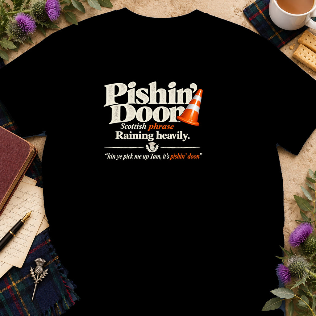 A black t-shirt printed with white and orange text defining the Scottish phrase Pishin Doon with a traffic cone graphic.