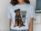 Light blue t-shirt with a sitting Rottweiler and text "SECURITY SYSTEM HAS PAWS."