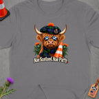 Highland cow wearing tartan with sunglasses and traffic cone, "Nae Scotland, Nae Party."