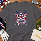 A charcoal gray t-shirt with a patriotic golf graphic on a wooden surface with golf accessories.