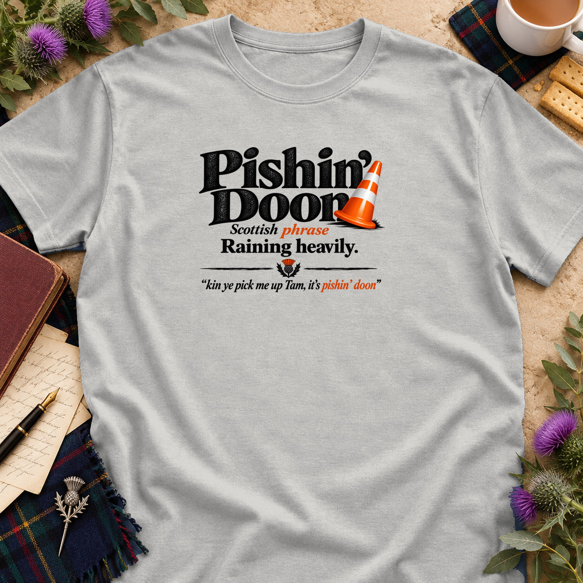 Light grey t-shirt featuring the text Pishin Doon, defined as a Scottish phrase for raining heavily.