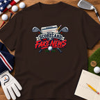 Brown t-shirt featuring a golf graphic with crossed clubs, a scorecard, and text reading The Scorecard Is Fake News.