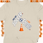 Beige t-shirt with "You Say Soccer, I Say Football" text and a soccer ball.