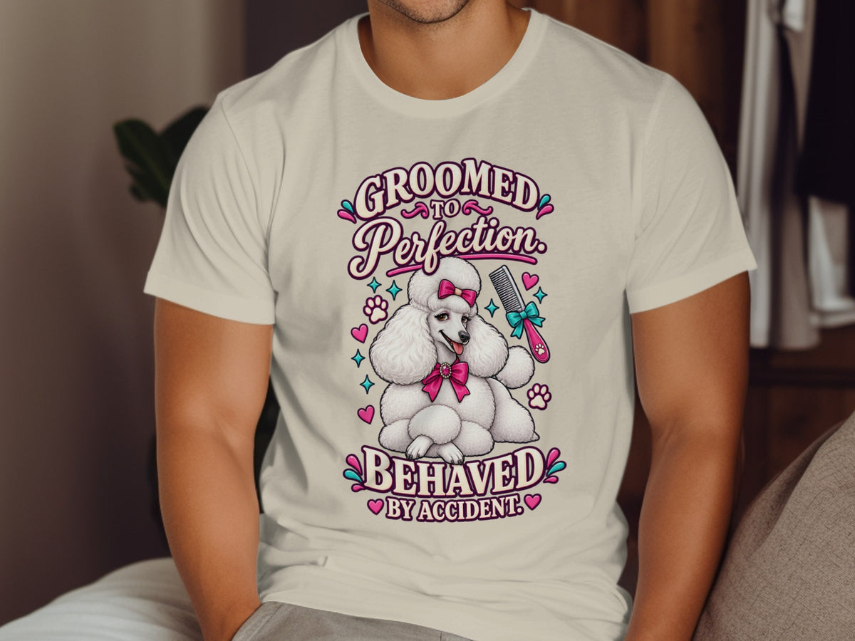 White poodle with pink bow, holding comb, with text "Groomed to Perfection. Behaved by Accident."