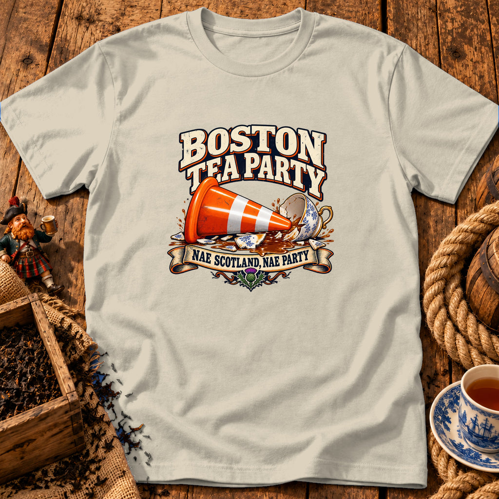 A cream-colored t-shirt with graphic art depicting a traffic cone tipping over a broken teacup spilling liquid, accompanied by the text Boston Tea Party and Nae Scotland, Nae Party.