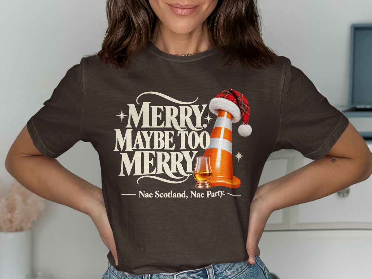 Brown t-shirt with "Merry Maybe Too Merry" text, traffic cone with Santa hat, whiskey glass.
