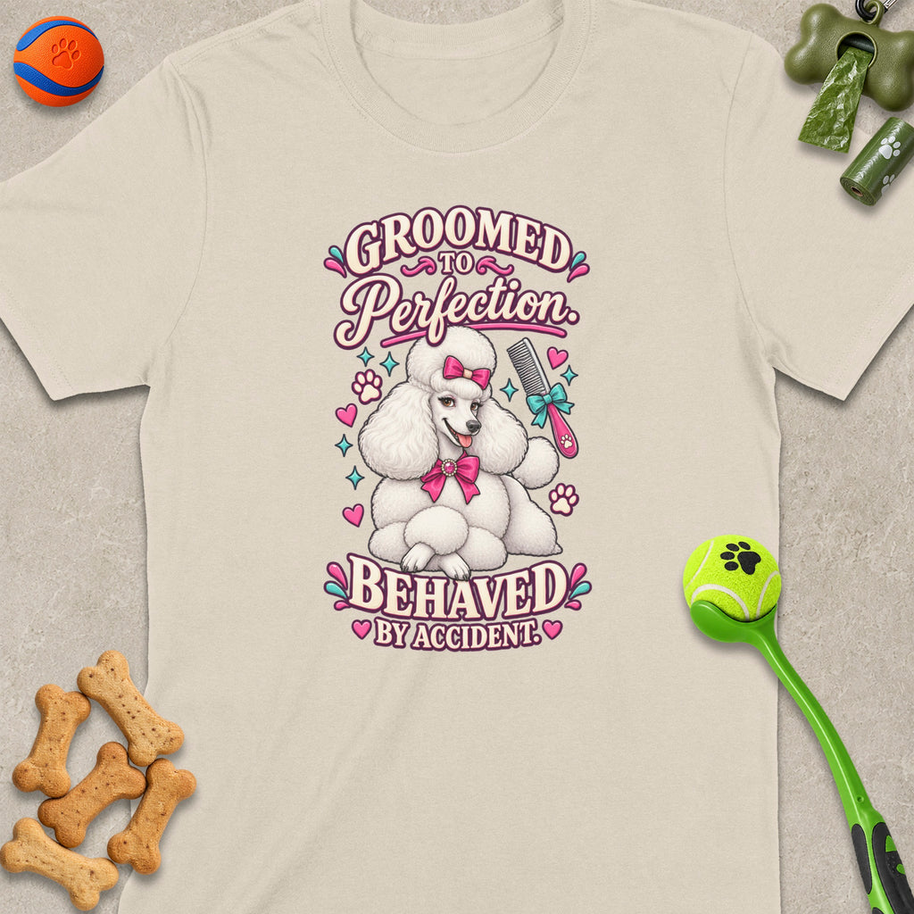 White poodle graphic on a cream t-shirt with text "Groomed to Perfection Behaved by Accident."