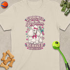 White poodle graphic on a cream t-shirt with text "Groomed to Perfection Behaved by Accident."