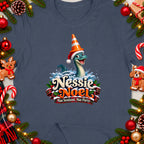 Nessie Noel graphic with text "Nae Scotland, Nae Party" on a t-shirt surrounded by Christmas decorations.