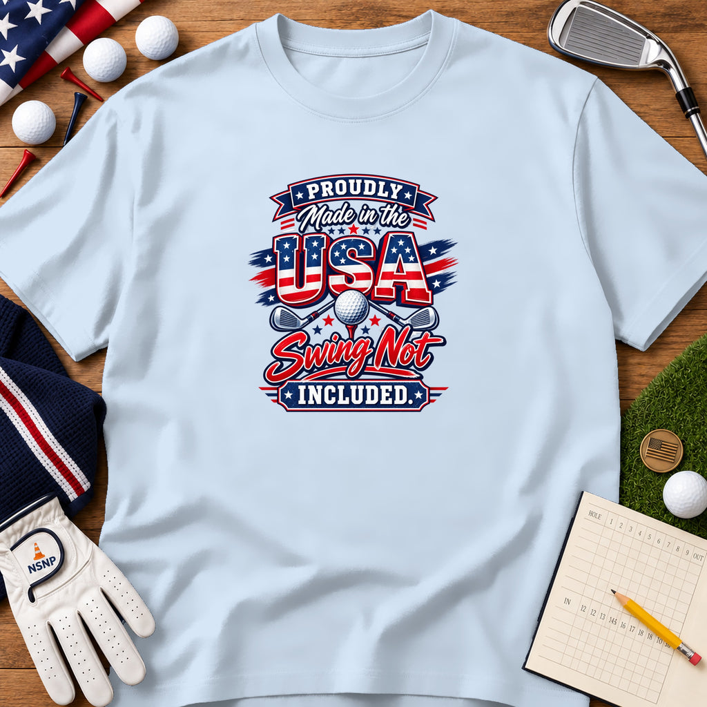 Light blue t-shirt featuring patriotic golf graphic and text surrounded by golf accessories on wood background.